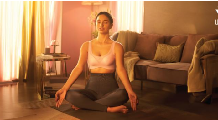 A confident woman wearing a soft-cup bra, smiling in natural light.